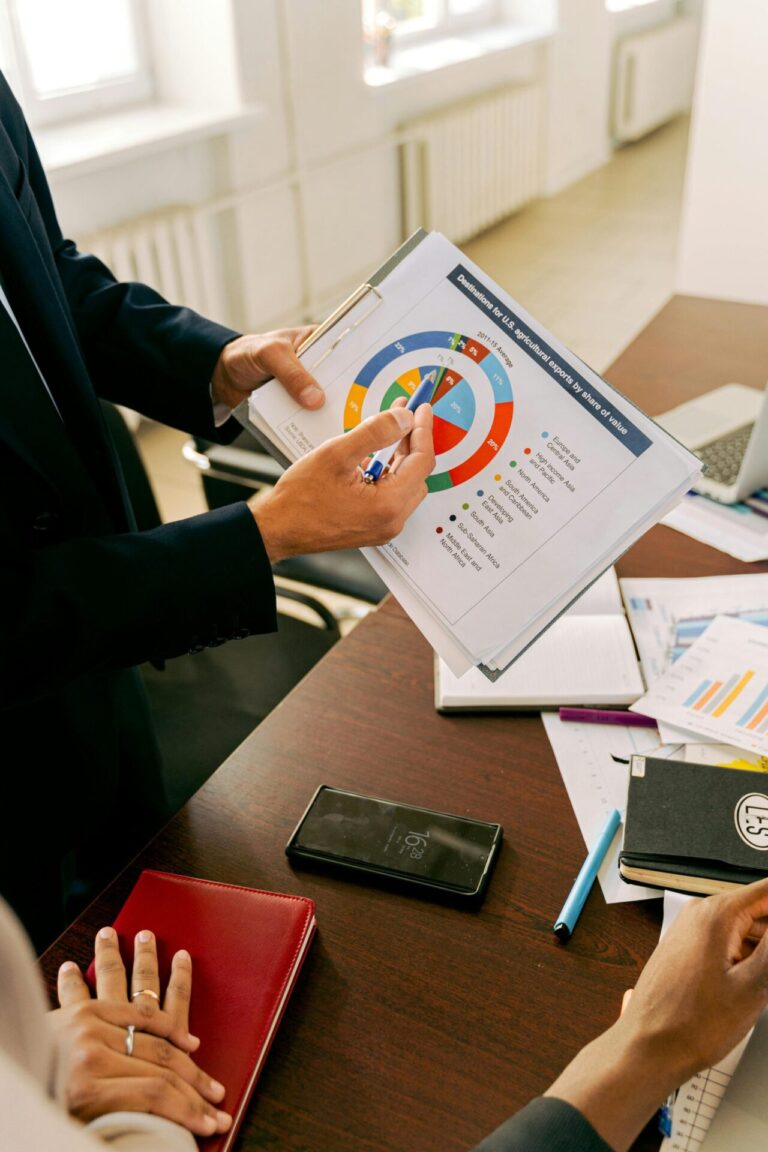 Consultant pointing to a chart on a clipboard during a client meeting